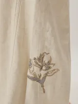 Pantalon de corte ancho y holgado, confeccionado en mezcla de algodón y lyocell. Presenta un diseño fluido con costuras verticales decorativas y bordado sutil en la pierna.