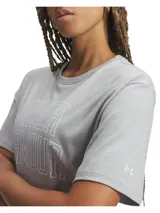 Remera Under Armour de manga corta color gris, con diseño holgado y estampado frontal con el nombre de la marca en estilo universitario.