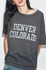 Camiseta de corte oversize confeccionada en algodón flamé, con cuello redondo y manga corta. Presenta un diseño con efecto desgastado, detalles de roturas en el tejido y estampado de texto a contraste en la parte frontal.