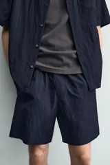 Bermuda relaxed fit de color azul marino confeccionada en tejido fluido con mezcla de viscosa, cintura elástica con cordón interior y bolsillos frontales.