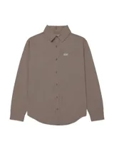 Camisa de manga larga color marrón taupe, confeccionada en 100% algodón, con cuello camisero, cierre frontal con botones, bolsillo en el pecho con etiqueta del logo de la marca y dobladillo redondeado tipo cola de camisa.