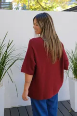 Sweater de punto color bordó, con cuello redondo, manga corta amplia y diseño holgado.