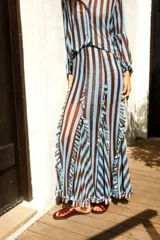 Falda larga de tul con diseño evasé, caracterizada por sus volados verticales y estampado de rayas en tonos azul y marrón. Posee cintura elástica para un ajuste cómodo.