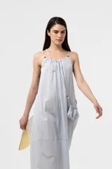 Vestido midi celeste de calce amplio y liviano, con escote fruncido regulable y breteles finos con detalles de cuentas. Presenta una silueta suelta e incluye una mini cartera desmontable al tono.