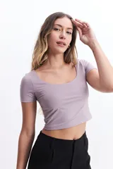 Remera cropped de manga corta, color lila claro, con escote amplio y ajuste al cuerpo.