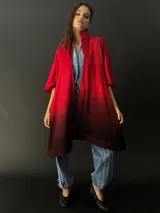Ruana roja con degradé a negro, confeccionada en lana merino teñida artesanalmente. Presenta cuello plisado en fieltro de lana merino.
