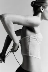 Corsé strapless color beige claro, con copas con aros y estructura de varillas verticales. El tejido es semitransparente con pequeños lunares visibles. Presenta un cierre frontal con ganchos.