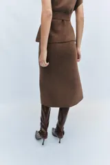 Falda midi de punto color crudo, con tiro medio, cintura elástica y diseño evasé.