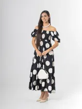 Vestido largo de lunares con escote bote y hombros descubiertos, mangas cortas abullonadas, cuerpo con nido de abeja y falda amplia.