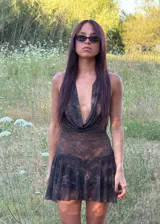 Vestido corto de estilo bohemio con cuello halter y escote drapeado. Confeccionado en tela traslúcida con estampado abstracto en tonos chocolate y negro, presenta una falda con vuelo y short incorporado para mayor comodidad.