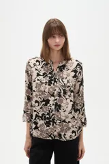 Camisa holgada de viscosa con cuello mao, mangas largas y estampado floral en tonos beige, marrón y negro, con dos bolsillos frontales con solapa.
