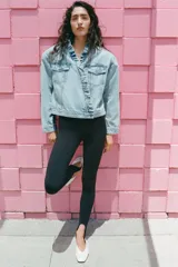 Cazadora de denim color celeste con cuello alto y volantes en el borde frontal. Cuenta con cierre cruzado con botones metálicos y bolsillos en el pecho con solapa.