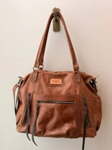Bolso maternal de cuero marrón con doble asa de hombro, correa ajustable, múltiples bolsillos frontales y laterales con cierre, y detalles de tiras trenzadas.