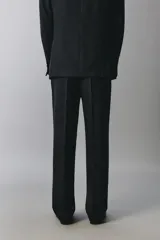 Pantalón de traje negro de corte regular fit, con pinzas delanteras, bolsillos laterales y cierre frontal con cremallera y botón.