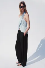 Pantalón tiro alto negro, con cintura elástica ajustable con cordones, bolsillos delanteros y detalle de pliegues en la parte frontal.