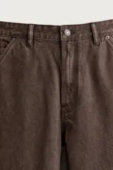 Pantalón jeans relaxed fit de color marrón con efecto lavado, de corte recto y estilo carpintero. Cuenta con bolsillos laterales, bolsillos traseros, bolsillos aplicados y tira multifunción en la pierna. Cierre frontal con cremallera y botón metálico.