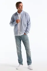 Campera estilo Harrington de corte clásico con diseño de rayas finas verticales en tono celeste y blanco. Cuenta con cuello alto, cierre frontal completo, bolsillos diagonales con solapa y botones, además de puños y dobladillo elastizados. Presenta el logo bordado del pingüino característico en el pecho.