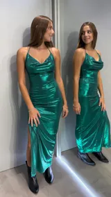 Vestido largo de fiesta en color verde esmeralda con acabado metalizado. Presenta un escote drapeado tipo cowl, tirantes finos ajustables y una abertura lateral pronunciada en la falda. El diseño es entallado al cuerpo.