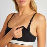 Top de lactancia negro con tirantes ajustables y broches para facilitar la alimentación. Presenta una banda elástica blanca con una línea negra en el borde inferior.