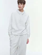 Buzo de cuello polo con escote en V abotonado, mangas raglán y puños acanalados. Presenta un diseño holgado y confortable en color gris melange.