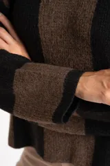 Sweater de tejido de punto grueso, con diseño de rayas verticales anchas en tonos marrón oscuro y negro. Presenta cuello redondo y mangas largas.