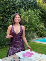 Vestido corto negro con estampado de plumas doradas, escote en V, breteles finos cruzados en la espalda, cut-outs laterales y volado en el ruedo.