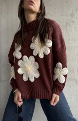 Sweater de punto color chocolate con diseño de flores grandes en relieve en color crema y centro amarillo. Presenta cuello alto, mangas largas y corte holgado.