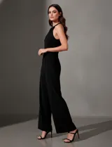 Enterito largo de crepe color rojo, con escote halter anudado y pierna ancha. Presenta bolsillos delanteros y abertura en la espalda con cierre invisible y botón.