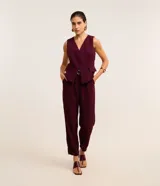 Pantalón zanahoria color borgoña de crepé de poliéster, con trabillas en la cintura, cierre tradicional, pliegues y bolsillos.