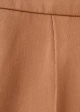 Short tipo falda pantalón de tiro bajo, color tostado, con diseño de tablas y bolsillos laterales.