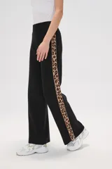 Pantalon de tejido de punto color crema, de corte ancho y tiro alto. Presenta una franja lateral con estampado animal print a lo largo de ambas piernas.