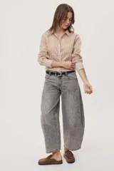 Jean de tiro medio y corte barrel con pierna amplia y ligeramente curva, estilo de cinco bolsillos en denim negro lavado.