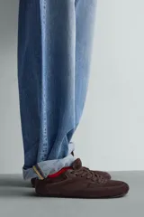 Zapatilla de cordones para hombre, confeccionada en piel con acabado de serraje en color beige. Presenta un diseño de perfil bajo con detalles de pespuntes decorativos y una suela ultrafina.