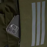Mochila Adidas Primelift color verde militar con base negra, compartimento principal amplio, bolsillo frontal con cierre y tres franjas reflectantes verticales.