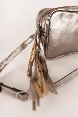 Cartera bandolera rectangular de cuero color plateado con correa fina ajustable y cierre con flecos.