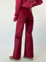 Pantalón de corte recto y tiro medio, confeccionado en pana color bordó. Presenta costuras verticales decorativas en el frente, cierre con botón y bolsillos laterales.