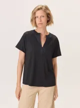 Remera negra de manga corta con escote en V y cuello redondo abierto. El cuerpo de la prenda tiene un acabado brillante o con lurex, mientras que el cuello es de un material liso y opaco.