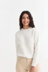 Sweater de punto con textura tipo waffle, color blanco, de corte clásico con cuello redondo y mangas largas.