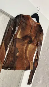 Top de microtul con estampado abstracto en tonos marrones. De manga larga y cuello redondo.