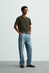 Camiseta de algodón de peso medio, color gris oscuro con efecto lavado ligero. Presenta cuello redondo y manga corta.