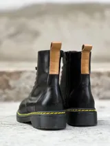 Bota negra de cuero charol con cordones, suela track color caramelo y tirador trasero.
