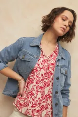 Blusa blanca con finas rayas verticales negras, de manga corta con volados y escote en V con pequeños botones y detalle de volado en el borde.