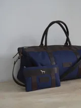 Sobre tipo cartuchera de lona con estampado de camuflaje y terminaciones en cuero marrón.