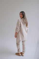 Campera tipo parka de color beige, con cierre frontal completo, capucha con cordones ajustables y mangas tres cuartos con detalle de trabilla y botón.
