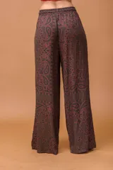Pantalón palazzo de tiro medio con cintura elástica y cordón ajustable. Presenta un diseño de corte amplio y fluido con un estampado de motivos paisley en tonos marrones y azul oscuro.