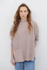 Buzo de tejido de punto en color beige, con cuello redondo, mangas largas y un bolsillo frontal aplicado. Presenta un diseño holgado con aberturas laterales en el ruedo.