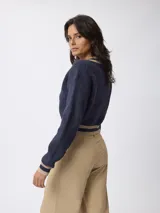 Sweater de punto estilo preppy, color blanco con detalles de rayas negras en el escote en V, puños y ruedo. De corte holgado y manga larga.