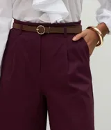 Pantalón tipo pantacourt de sastrería en color bordó, con pliegues delanteros, cintura con trabillas y cierre frontal. Presenta un corte amplio y sofisticado, e incluye un cinturón fino desmontable.