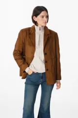 Chaqueta de gamuza color marrón con solapas clásicas, cierre frontal de botones y bolsillos laterales. Presenta un corte recto y estructurado.