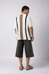 Remera de tejido de punto con textura piqué, de manga corta y corte relajado. Presenta un diseño de rayas verticales en tonos blanco, negro y marrón.